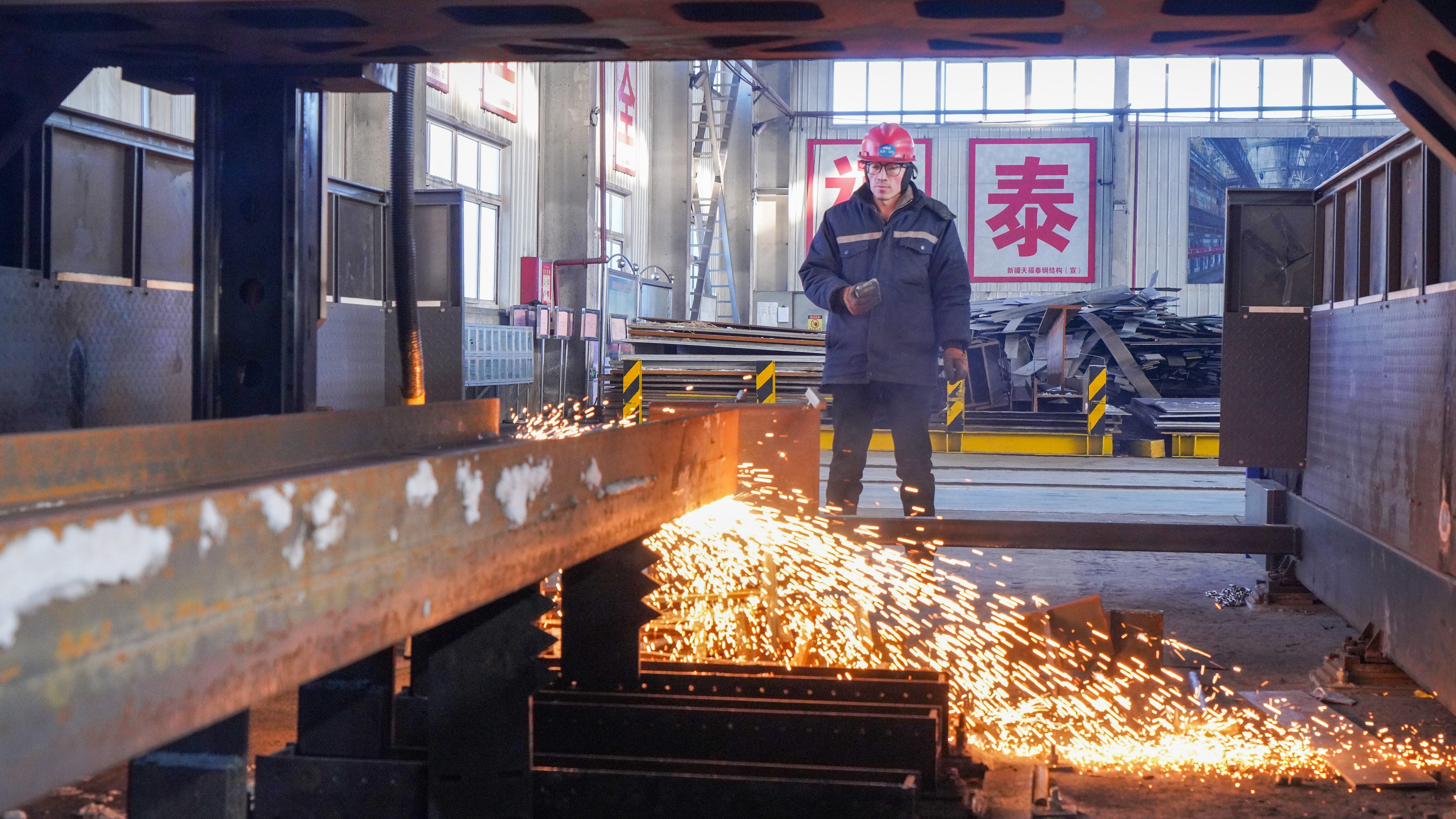 1月18日,工人在新疆天福泰钢结构有限公司生产车间操作自动化焊接设备